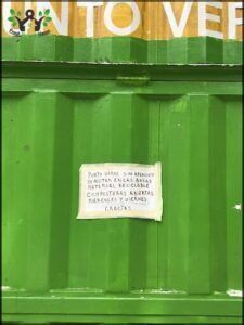A sign on a green door reads "Puerto Hate Sam Antena Material Recicable".