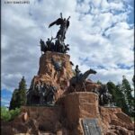 A statue of a man holding a sword is surrounded by a group of people.