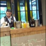 arafed man behind a bar with drinks and drinks in front of a window