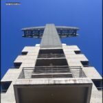arafed view of a tall building with a balcony and a sky background