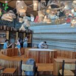 people are sitting at tables in a restaurant with wooden tables and chairs