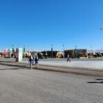 people are walking down a road with kites in the sky