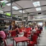 people sitting at tables in a large indoor area with skylights