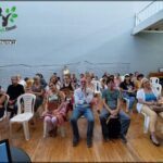 people sitting in chairs in a room with a crowd of people