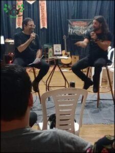 people sitting in chairs in a room with a microphone and a guitar