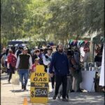 people walking down a street with a sign that says hay gas works $ 500