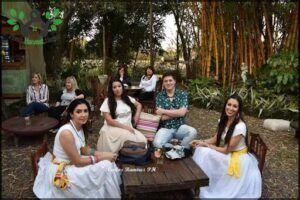 several women sitting around a table in a garden with a group of people