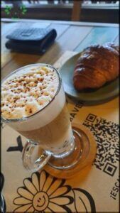there is a glass of coffee and a croissant on a table