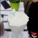 there is a large glass of milkshake with whipped cream and a small cup of chocolate