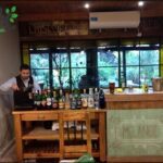 there is a man standing behind a bar with bottles of alcohol