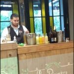 there is a man standing behind a bar with bottles of drinks