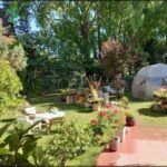 there is a small garden with a greenhouse and a table and chairs