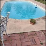 there is a small pool in the backyard with a chair and table