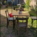 there is a table and chairs in the yard with an umbrella