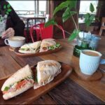there is a woman taking a picture of a sandwich on a plate