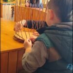 there is a young boy that is looking at a bird cage