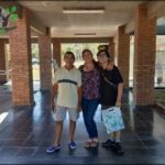 Three people pose for a photo in front of a building.