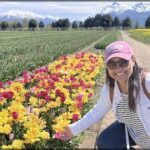woman kneeling in a field of flowers with mountains in the background