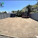 A backyard with a swing set and a garden hose.