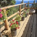 A beautiful view of the mountains from a deck with potted plants and flowers.