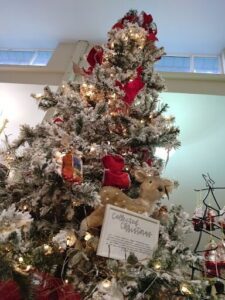 A beautifully decorated Christmas tree with a teddy bear and a sign that reads "Collected Christmas".