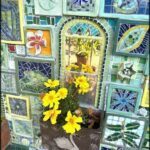 A beautifully decorated wall with a vase of yellow flowers and a bird statue.