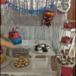 A birthday party with a Spider-Man theme, featuring a cake, cookies, and a balloon.