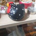 A black and red rooster figurine sits on a shelf.