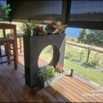 A black planter with flowers sits on a wooden deck.