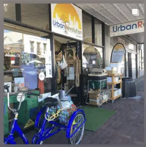 A blue bicycle is parked outside a storefront with a sign that reads "urban revolution."