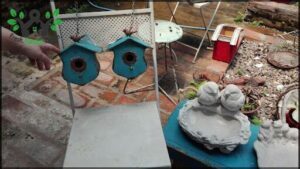 A blue chair with a birdhouse on it sits in front of a blue table.