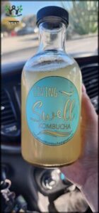 A bottle of living swell kombucha is being held by a person.