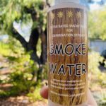 A bottle of Smoke Water is being held by a person.