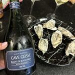 A bottle of wine is displayed next to a plate of oysters.