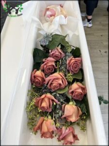 A bouquet of roses is placed in a casket, creating a beautiful and heartfelt display.