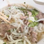 A bowl of soup with noodles and meat in it.