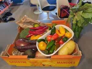 A box of assorted fruits and vegetables sits on a table.