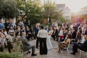 A bride and groom stand together in front of their wedding guests.