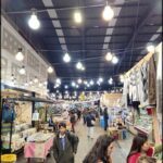 A bustling marketplace filled with people shopping and vendors selling their wares.