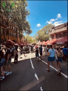 A bustling street scene with people walking and standing, and a large group of people gathered in a marketplace.