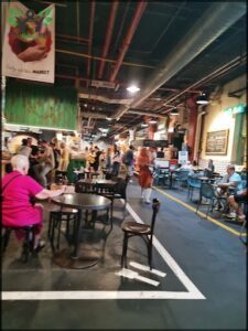 A busy marketplace with people walking around and sitting at tables.