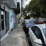 A car is parked on the side of a street, next to a building.