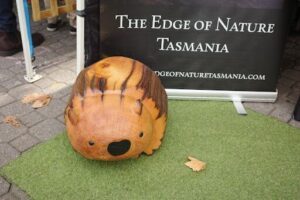 A carved wooden beaver sits on a green surface.
