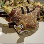 A close up of a decorative dragon head with a yellow and brown color scheme.