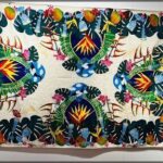A colorful and intricate tapestry featuring tropical flowers and leaves.