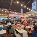 A crowded restaurant with people eating and drinking.