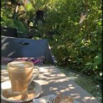 A cup of coffee sits on a table next to a slice of cake.