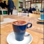 A cup of coffee with a chocolate topping sits on a table.