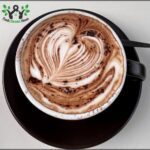 A cup of coffee with a heart shaped foam on top.