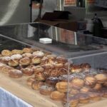 A display case filled with a variety of pastries, including croissants and donuts, is ready for customers to enjoy.
